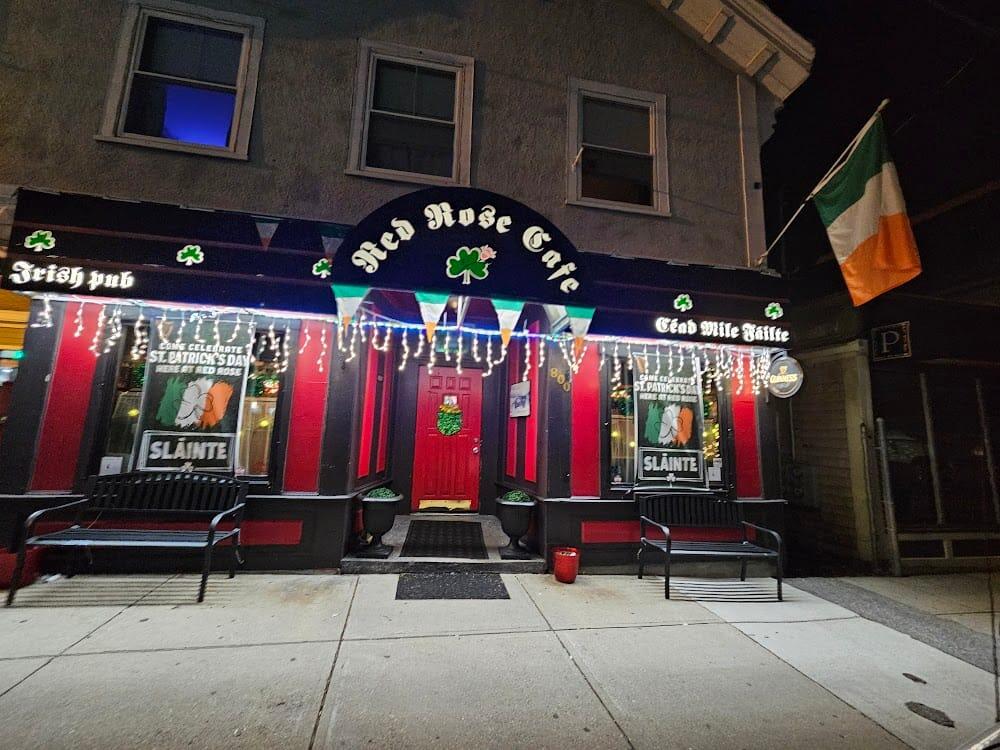 Red Rose Cafe storefront at night with the Irish flag and lit arched sign