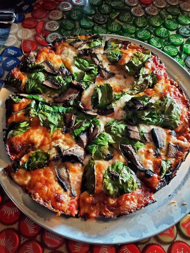 Red Rose signature thin-crust bar pizza on a metal tray over a bottle-cap table